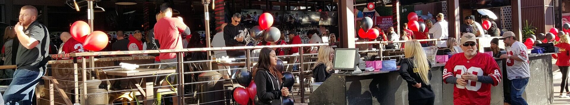 Outdoor seating area with red balloons and a lively atmosphere.